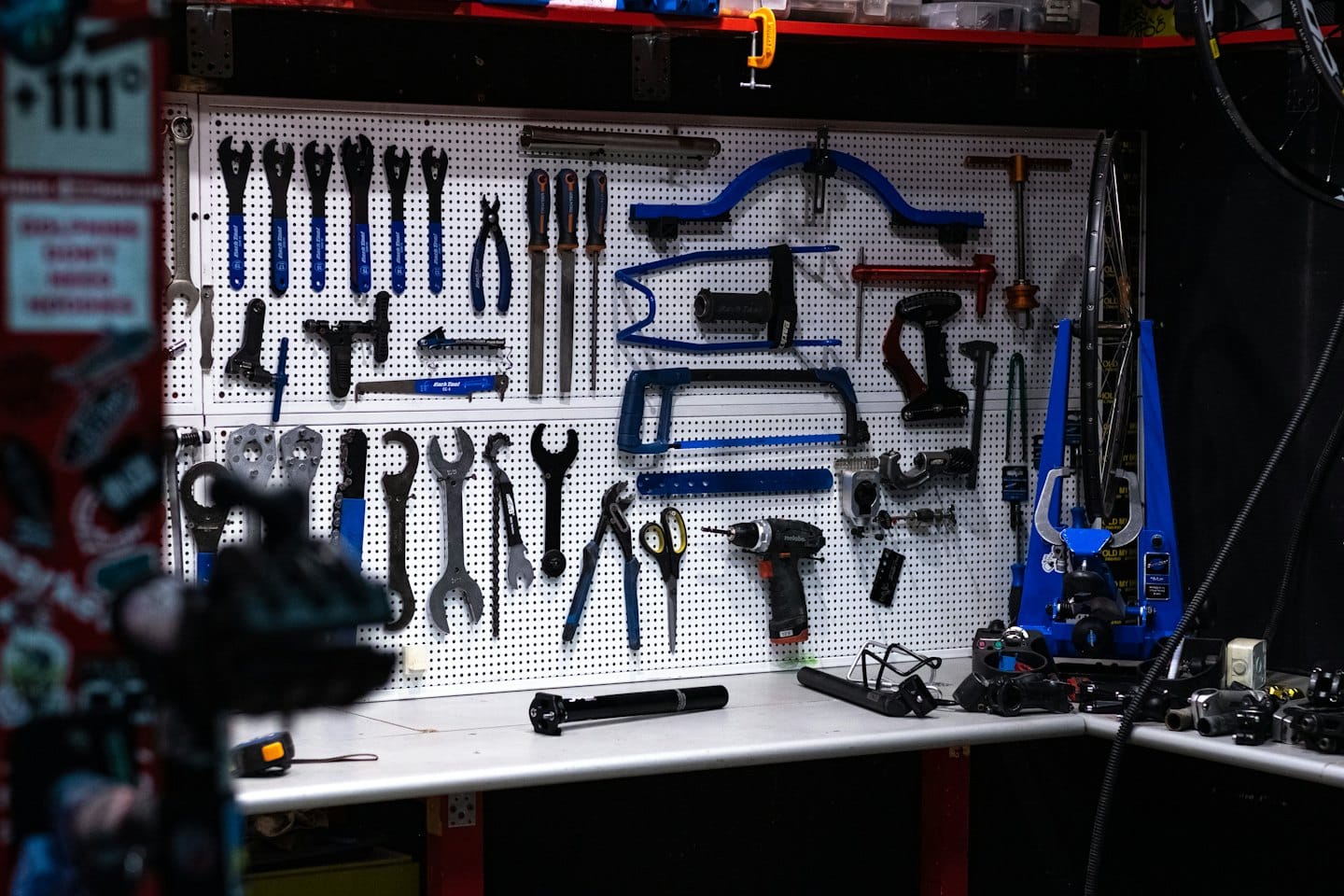 Pegboard wall with organized bicycle repair tools and workbench.
